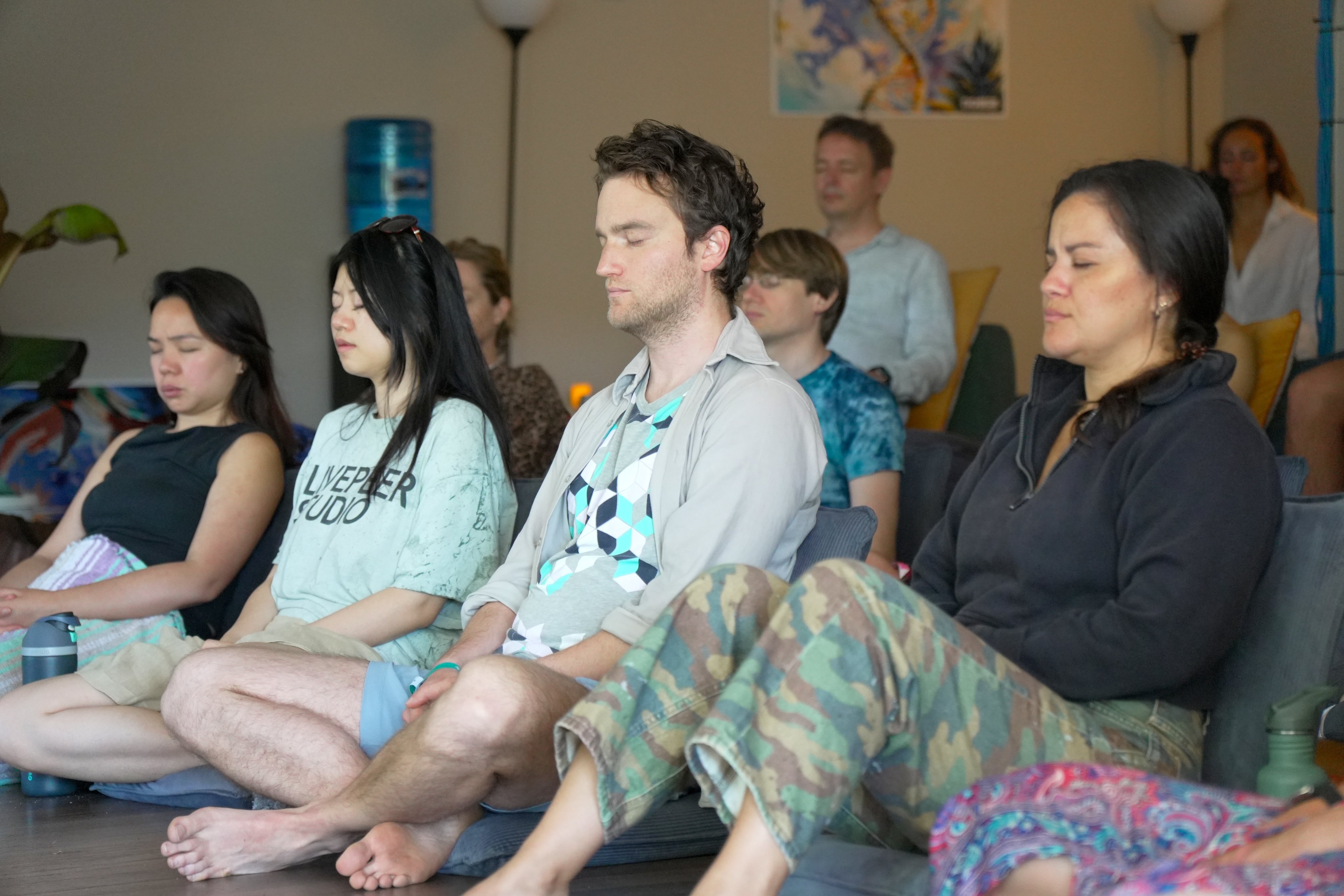 Group meditation practice with participants seated in a classroom