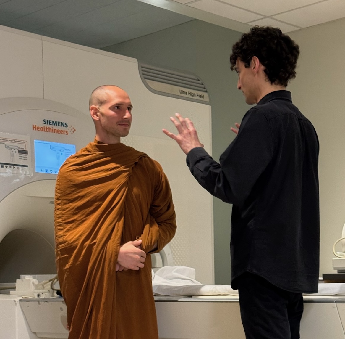 A researcher speaks with a monk in ochre robes in a research lab